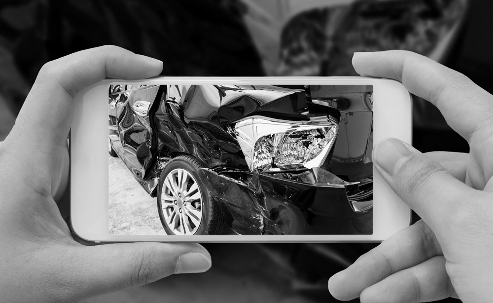 A Man Taking A Photo Of A Damaged Car